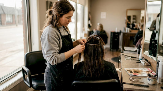 Stylist sewing hair weft into client's hair