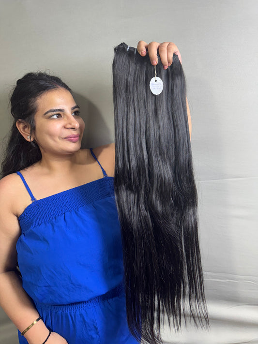 Long dark straight hair bundle with visible weft, held up by a person